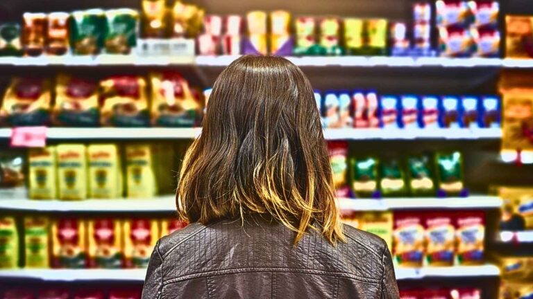 A woman shopper is staring at products on a grocery shelf.